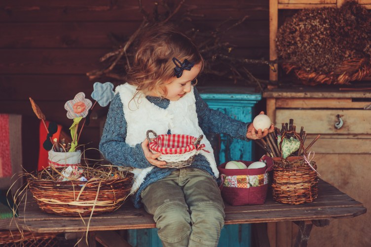 child girl playing with easter eggs and handmade decorations in cozy country house